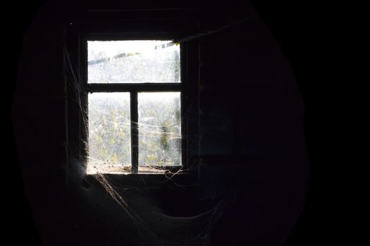 Old dirty window with cobweb around and darkness inside
