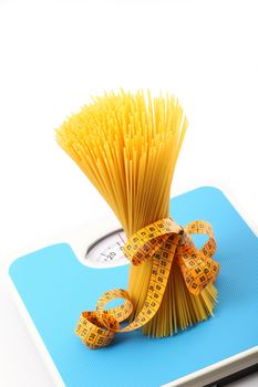 italian raw pasta on white background with bathroom scale