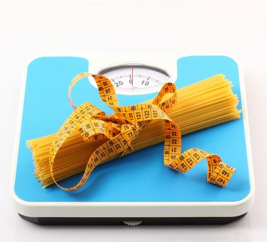 italian raw pasta on white background with bathroom scale