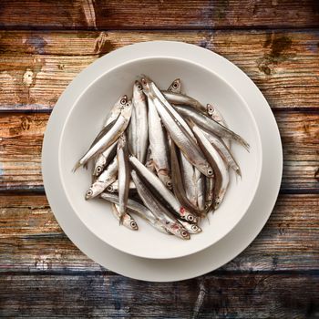 dish of fresh anchovies on wooden background