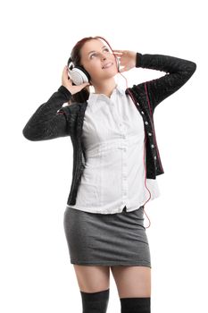 Beautiful young student girl in school uniform with headphones listening to music, isolated on white background. Portrait of a young beautiful woman enjoying music on her headphones. Music concept.