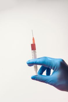Hand in glove with syringe on white background. Injections.
