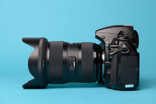 Professional modern DSLR camera against blue background