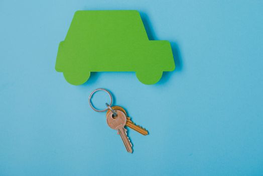 paper green cars figure with keys. top view on blue background