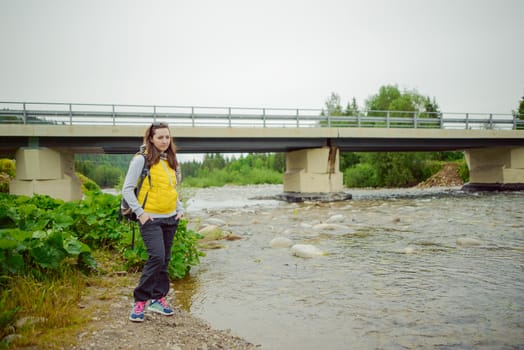 Female tourist standing beside the mountain river.
