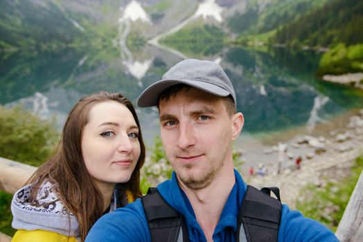 Happpy couple taking selfie withe lake background in the mountains
