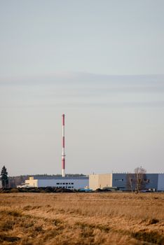 modern exterior of an industrial building, surrounded by a fence with iron gate