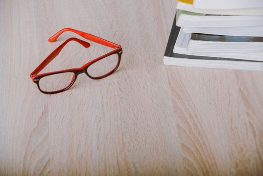 book and eyeglasses on wood background desk