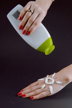 woman applying sunscreen cream on Hand. Red nails.