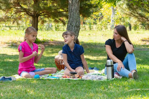 Two girls and a girl talking on a picnic