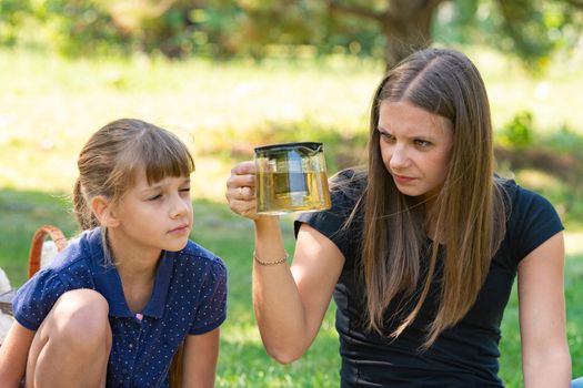 Girl and girl with interest look at a teapot at a picnic