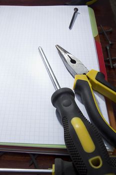 Screwdriver and pliers on a checkered notebook