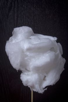 White cotton candy on a stick on a black background