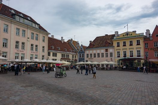 Tallinn, Estonia - July 29, 2017:   Tourists crowd the sidewalk cafes and shops in the medieval Tallinn Town Square in the walled city of Tallinn Estonia.