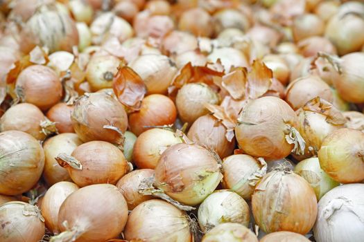 Seasonal vegetables are stacked in boxes at the grocery store. Yellow onions shot close-up. Natural products for cooking healthy food.