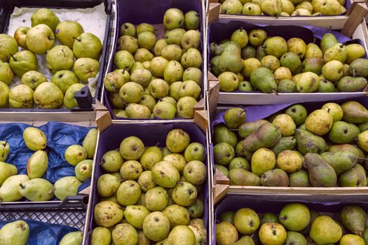 Seasonal fruits are placed in boxes in the grocery store. Close-up of fresh pears. Natural foods rich in vitamins for a healthy diet.