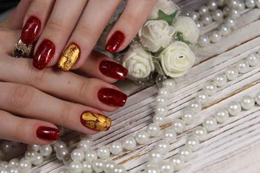 Hands with long artificial manicured nails colored with red nail polish