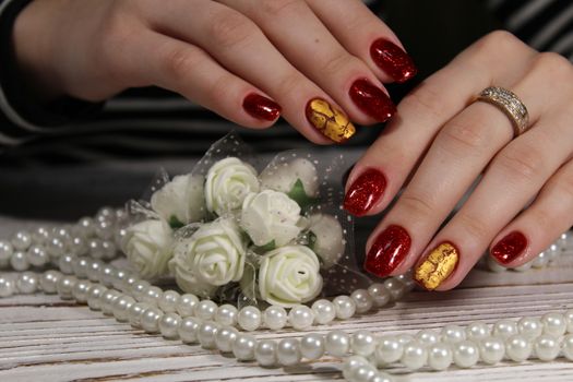 Hands with long artificial manicured nails colored with red nail polish