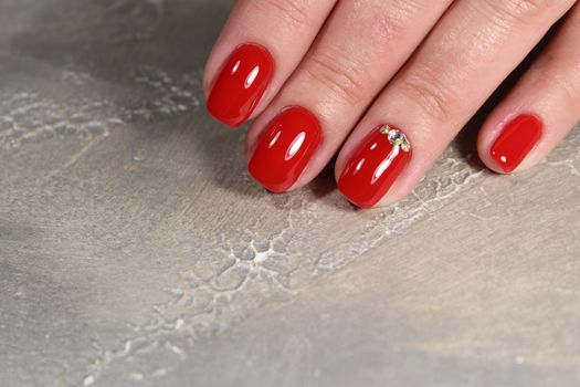 Hands with long artificial manicured nails colored with red nail polish