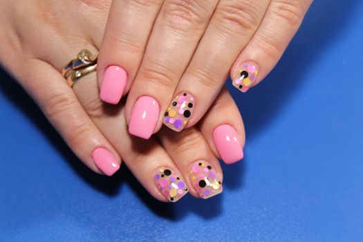 Stylish trendy female manicure. Beautiful young woman's hands on pink and blue background.