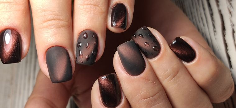 Glamorous luxurious brown crocodile manicure with gold plated women's nails closeup.