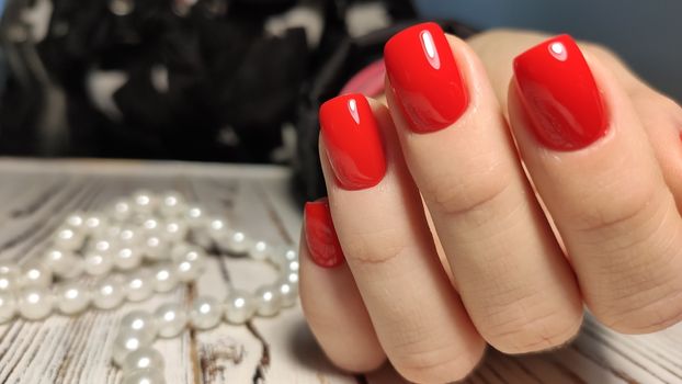 Hands with long artificial manicured nails colored with red nail polish