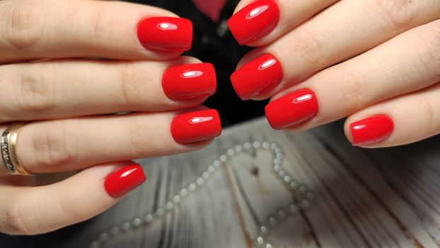 Hands with long artificial manicured nails colored with red nail polish