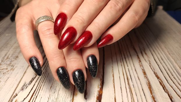 Hands with long artificial manicured nails colored with red nail polish