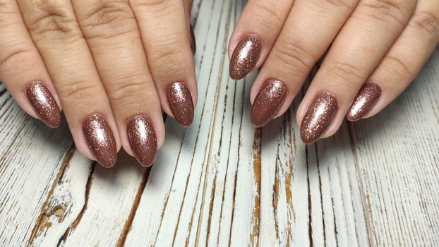 Glamorous luxurious brown crocodile manicure with gold plated women's nails closeup.