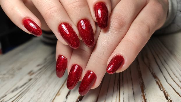 Hands with long artificial manicured nails colored with red nail polish