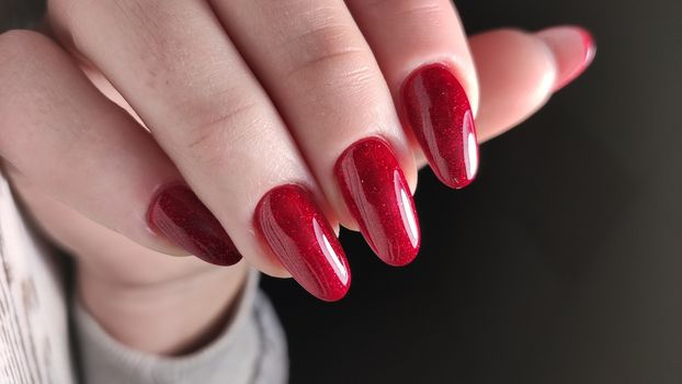 Hands with long artificial manicured nails colored with red nail polish