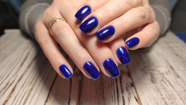 Closeup of hands of a young woman with dark red manicure on nails against white background