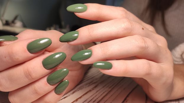 Closeup of hands of a young woman with dark red manicure on nails against white background