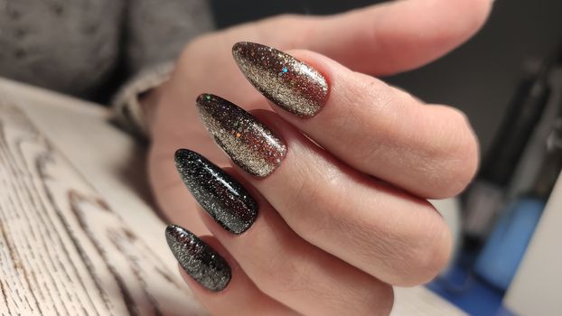 Closeup of hands of a young woman with dark red manicure on nails against white background