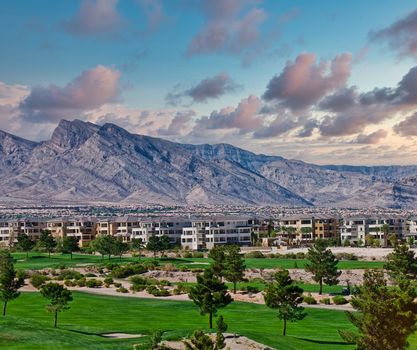 A golf course by a condo complex in front of a mountain range