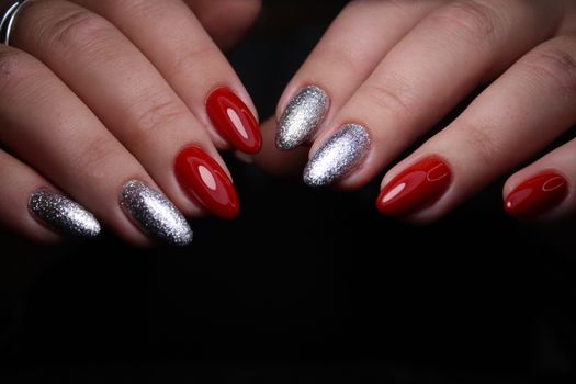Closeup of hands of a young woman with dark red manicure on nails against white background