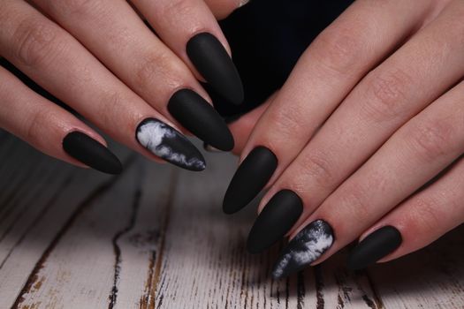 Closeup of hands of a young woman with dark red manicure on nails against white background