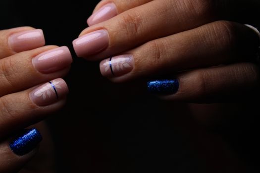 Closeup of hands of a young woman with dark red manicure on nails against white background