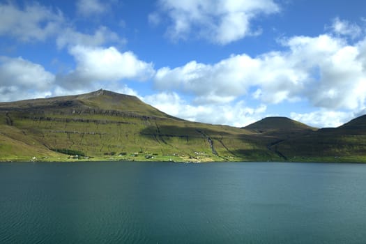 Landscape of Faroe Islands showing blue sky, green mountains and fjord