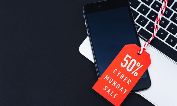Cyber Monday Sale text on red tag have mobile smart phone over laptop computer with red background
