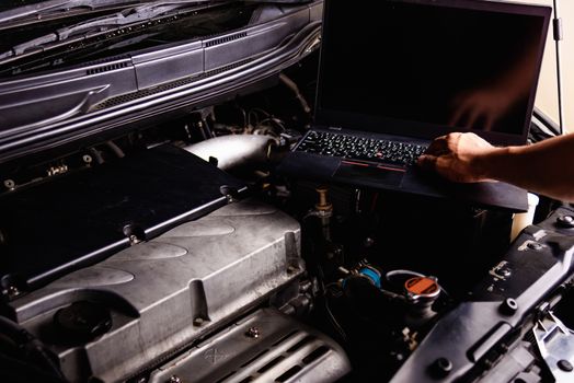 Laptop computer on car mechanic engine for service at workshop