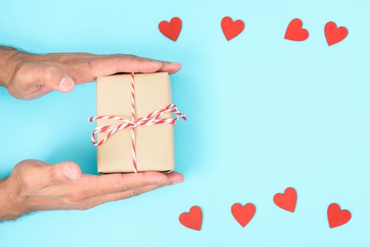 Valentine's Day Concept, Top view Flat lay, have red heart and hand holding gift box on blue background with copy space for your text