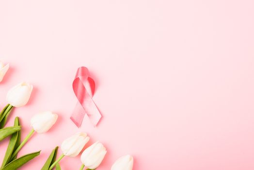 Breast cancer month concept, flat lay top view, pink ribbon and Tulip Flower on pink background with copy space for your text