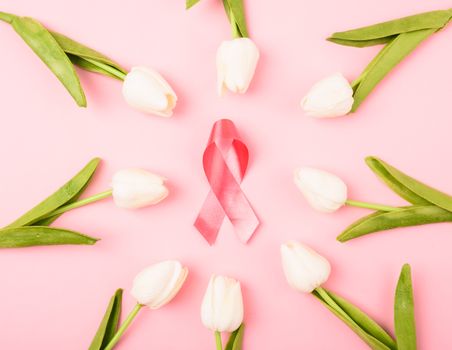 Breast cancer month concept, flat lay top view, pink ribbon and Tulip Flower on pink background with copy space for your text