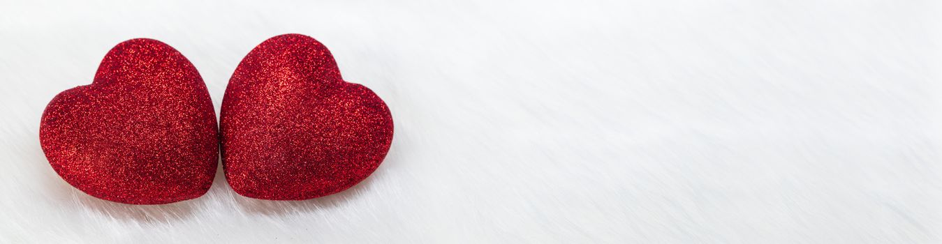 Two glitter hearts on white fur background with copy space for text