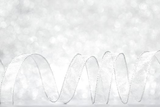 Shiny silver gift ribbon on bokeh background close-up