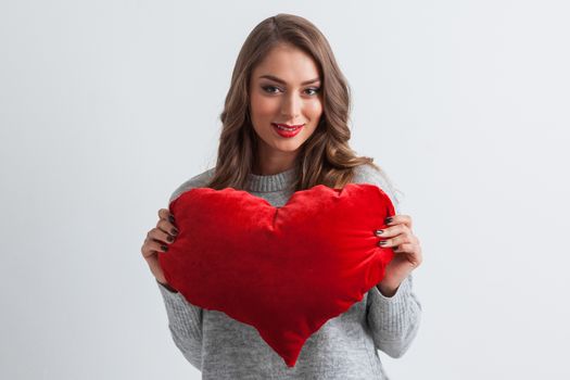 Beautiful woman with a big red heart shape pillow on white background