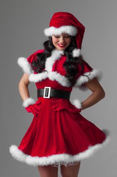 Beautiful woman in Santa Claus clothes on gray background