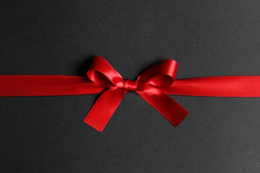 Elegant satin red ribbon bow on black background