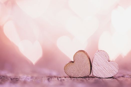Two handmade wooden hearts on beautiful pink bokeh background. Vintage style. Love Valentine's Day concept.